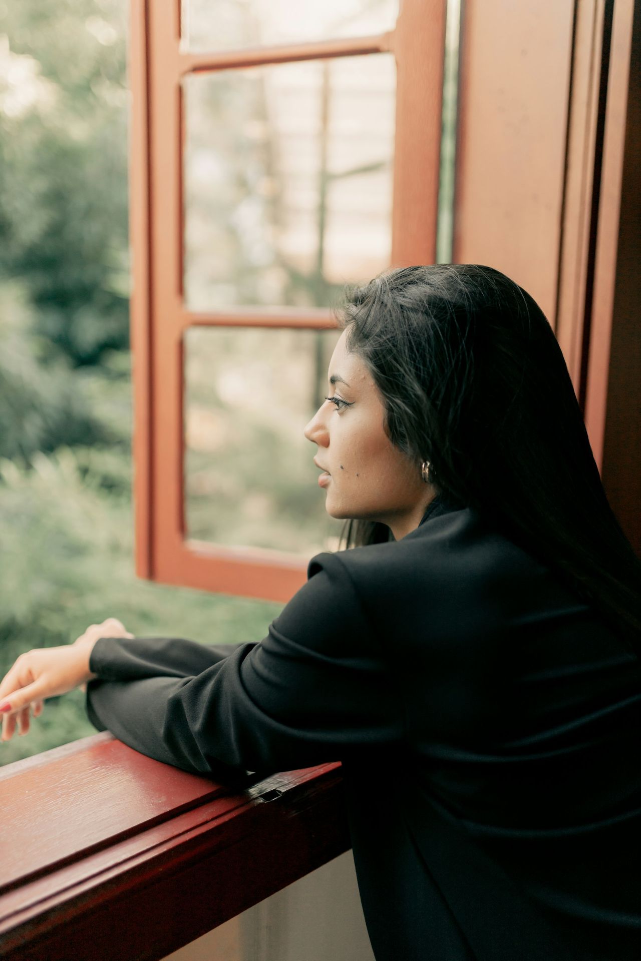 A woman looking out a window at a forest